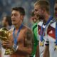 Mesut Özil yang bertelanjang dada memegang trofi Piala Dunia 2014 sambil mengenakan medali emas di lehernya, sebuah momen puncak dalam kisah Mesut Özil.